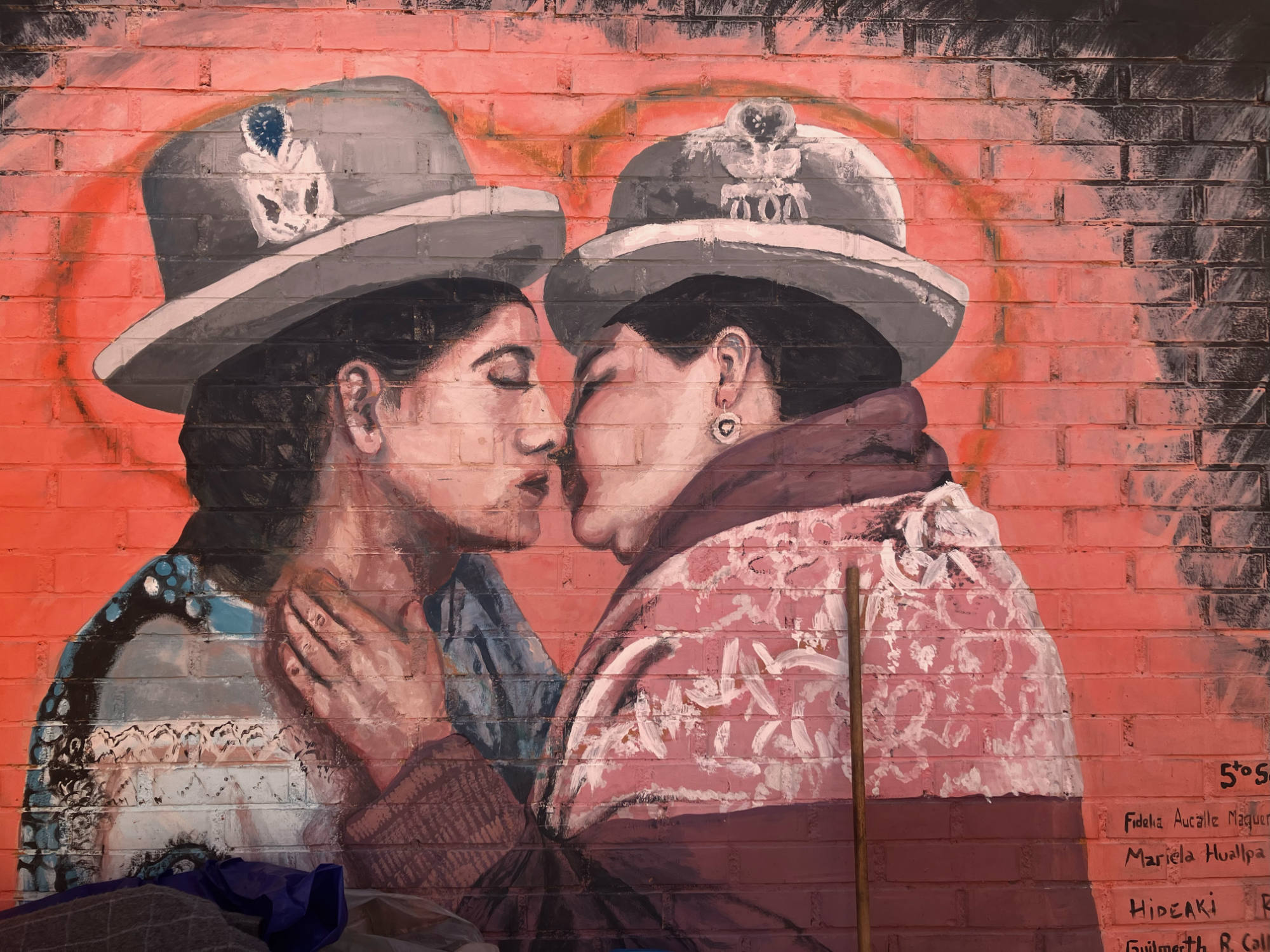 Colorful mural showing to women in Aymara attire almost kissing.